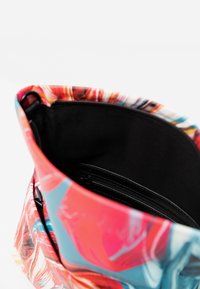Kolorowa torba na ramię z żywym wzorem w wir. Posiada czarne wnętrze i kieszeń na zamek, wykonana z elastycznego materiału.