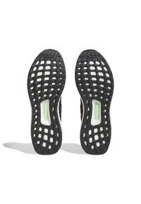 Sorte sneakersåler med et mønsteret greb og rundede udskæringer samt en grøn accent, der fremhæver et fleksibelt, tekstureret gummimateriale.