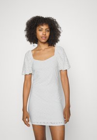 Vestido cinza claro com mangas curtas bufantes, decote quadrado, tecido texturizado com padrões de pontos e forma ajustada.