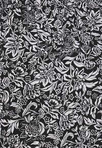 Tela negra con un patrón floral blanco que presenta flores y hojas grandes. El diseño es intrincado, con diversas formas y tamaños de pétalos.