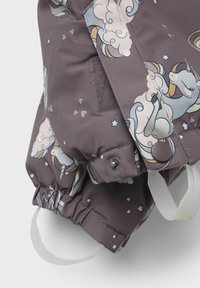 Tessuto impermeabile viola con motivo di unicorni e nuvole, dotato di polsini regolabili e bottoni a pressione. Superficie texturizzata con dettagli decorativi.