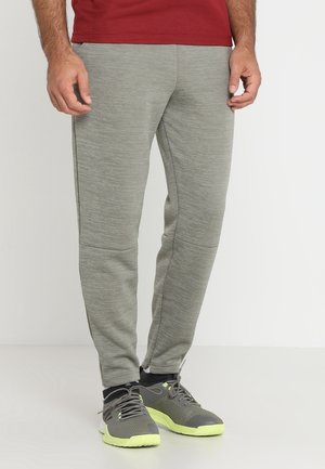 Grå, bløde løbebukser med en afslappet pasform, der har et struktureret stof og sidelommer. Kombineret med grå sneakers med neonfarvede accenter.