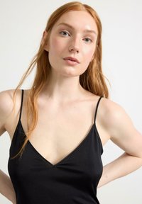 Schwarzwäsche mit dünnen Trägern, V-Ausschnitt-Design und glatter Textur. Der Stoff wirkt leicht und hat eine taillierte Silhouette.