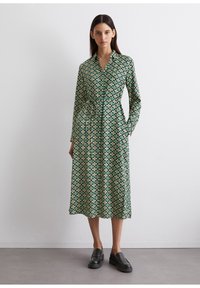 Abito verde a fantasia con scollatura a colletto, maniche lunghe, vita con cintura e orlo medio. Presenta forme geometriche in crema e blu.