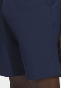 Tamsiai mėlynos spalvos šortai, pagaminti iš lengvos medžiagos. Turi tiesų kirpimą, įsiūtas šonines kišenes ir siūtas apačias. Lygi tekstūra, be matomų raštų.