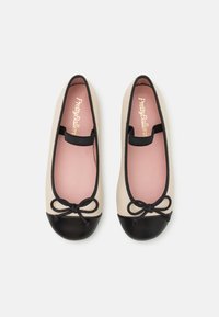 Ballettleiligheter med en beige kropp, svart tåhette og en svart sløyfe detalj. Innvendig har de en rosa foring. Kantene har kontrasterende søm.