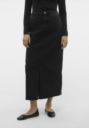 Black denim maxi skirt with a front slit, five-pocket design, and metal button closure. Paired with black, flat ballet shoes.
