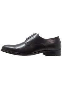 Chaussure habillée pour homme en cuir noir avec laçage fermé, finition lisse, petit talon et bout pointu vue de profil sur fond blanc.