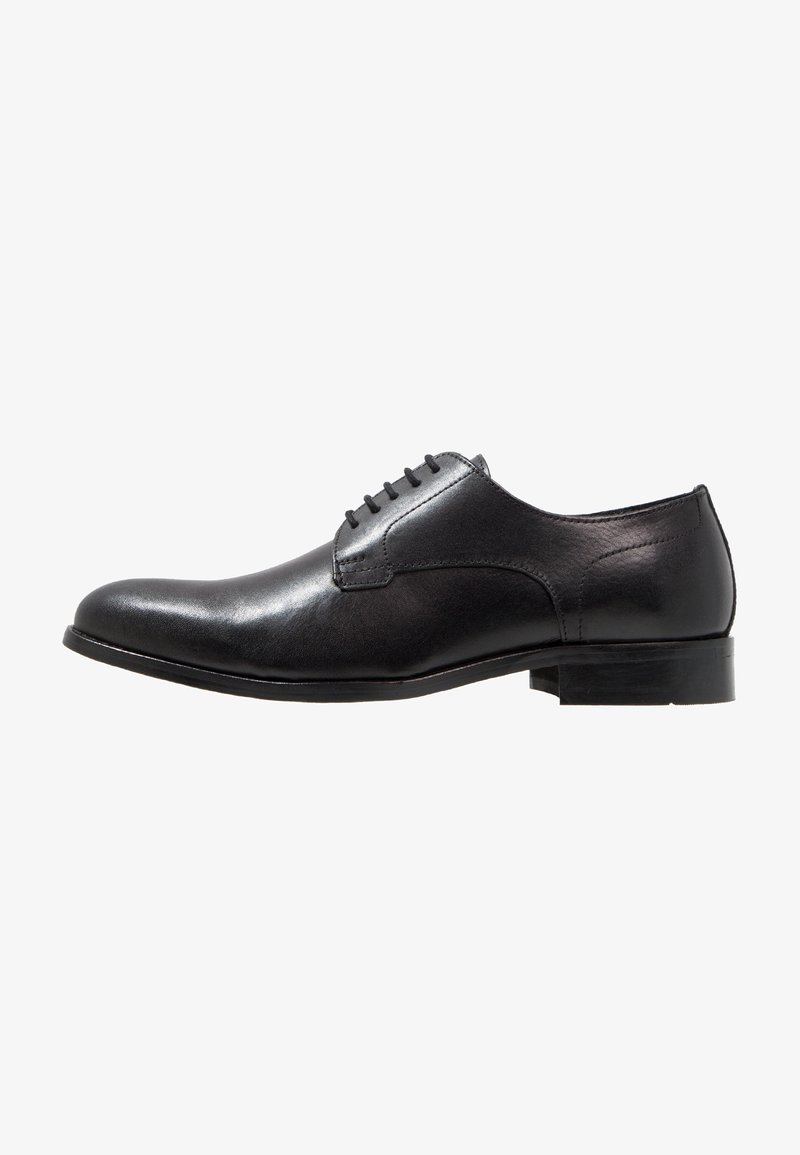 Chaussure habillée pour homme en cuir noir avec laçage fermé, finition lisse, petit talon et bout pointu vue de profil sur fond blanc.