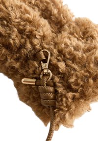 Material de piel marrón y texturizada con un cierre dorado brillante y detalles en cuero marrón. Presenta una correa trenzada de cuero.