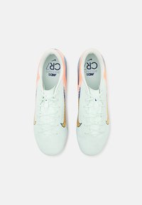 Scarpe da calcio di un verde menta chiaro con una leggera lucentezza, caratterizzate da accenti arancioni e blu navy, una superficie texturizzata e un design con lacci.