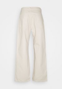 Kalhoty se širokými nohavicemi z lehké bavlny světle béžové barvy. Mají vysoký pas, dvě zadní kapsy a hladkou texturu s minimálními švy.