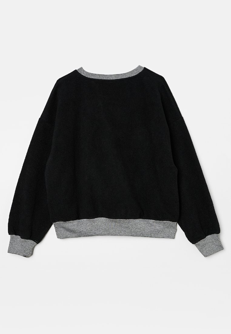 Sweatshirt en polaire noire à manches longues, avec un col rond et un ourlet et des poignets côtelés gris. Texture douce et coupe décontractée.