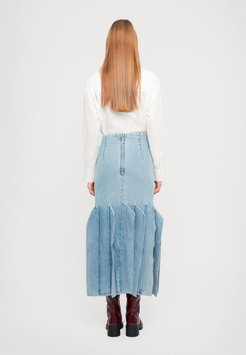 Jeansrok met een uitlopende, gelaagde ontwerp, rauwe zoom en ritsluiting achter. Gedirigeerd met een wit shirt en bordeauxrode knielaarzen.