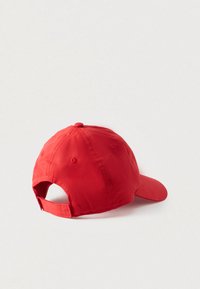 Κόκκινο καπέλο μπέιζμπολ με καμπυλωτή γείσα, κατασκευασμένο από μαλακό ύφασμα. Διαθέτει ρυθμιζόμενο λουράκι στο πίσω μέρος και οπές αερισμού στην κορυφή.