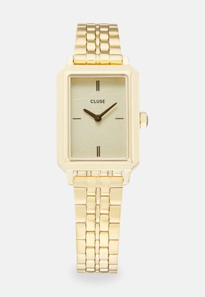 Montre-bracelet rectangulaire en or avec un cadran vert clair texturé, deux marqueurs d'heure noirs, un bracelet en métal doré et un design minimaliste.