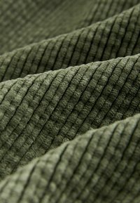 Soft, ribbed fabric in olive green, featuring textured vertical lines. The material appears plush with a slight sheen, emphasizing depth.