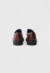 Burgunderfarbene Lederschuhe mit kontrastierenden Nähten, Gummisohle und runder Zehenpartie. Die Rückansicht zeigt detaillierte Nähte und gepolsterten Knöchelstütze.