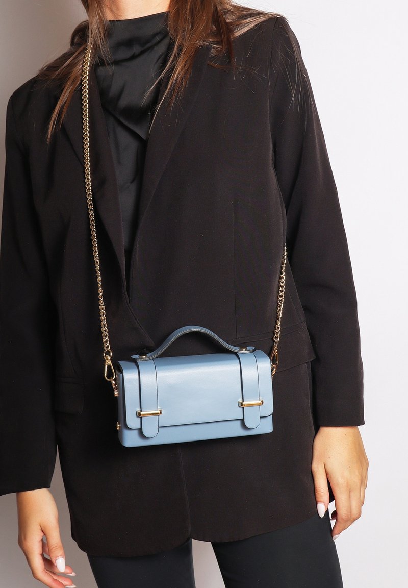 Borsa in finta pelle blu chiaro con un design strutturato, manico superiore e hardware color oro. Dotata di una tracolla a catena rimovibile.