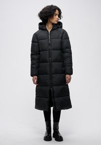 Juodas ilgas paminkštintas paltas su gaubtu, turi siuvinėtus skirtingus skyrius, priekyje užtrauktuko užsegimas ir tiesų kirpimą. Dėvimas ant juodų drabužių ir batų.