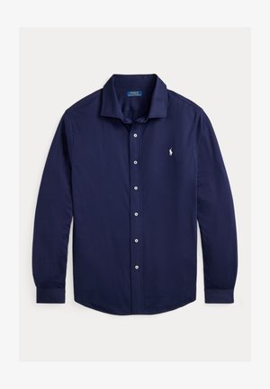 Tumši zils garām piedurknēm krekls, izgatavots no kokvilnas, ar pogājamu apkakli, priekšējo pogu aizdari un mazu izšūtu logotipu uz krūšu.