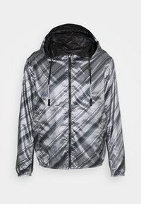 Silverreflekterande jacka med diagonala svarta ränder, huva, dragkedjestängning och sidofickor, med en slät, glänsande yta.