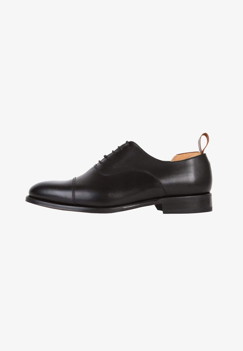 Scarpa oxford in pelle nera con finitura liscia, punta arrotondata, dettagli di cucitura sottili e tacco piccolo. Presenta un inserto posteriore per facilitare l'indossamento.
