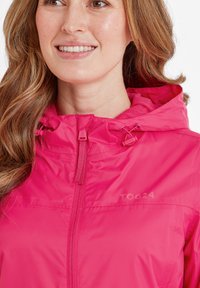 Bright pink waterproof jacket with a zip closure, drawstring hood, and logo on the chest. Smooth texture and lightweight design.