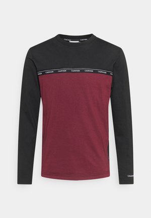 Haut pour homme à manches longues avec manches et haut de la poitrine noirs, corps bordeaux, et bande avec le logo "Calvin Klein" sur la poitrine et sur le poignet gauche.