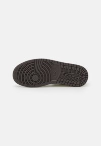 Sole di una sneaker nera Nike Air Jordan con motivi di battistrada circolari e a griglia su uno sfondo bianco piatto.
