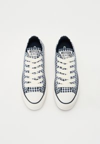 Jūraszila un baltā ģingham raksta tenisa apavi ar gumijas zoli, baltajām šņorēm un preču zīmes logo. Noapaļots pirksts un kontrastējoša apmale.