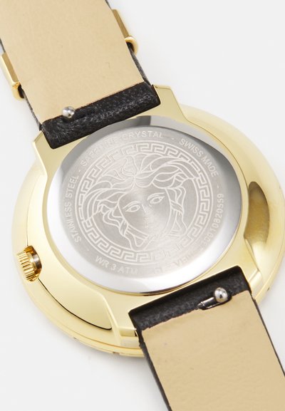 Ceas cu carcasă auriu, cu spate din oțel inoxidabil și un design gravat. Curea din piele neagră cu interior bej. Fabricat în Elveția, rezistent la apă.