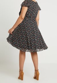 Czarna sukienka w kwiaty z krótkimi falbaniastymi rękawami, dopasowaną talią i rozkloszowanym dołem. Posiada małe, wielokolorowe kwiatki w rozproszonym wzorze.