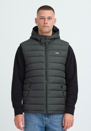 Gilet rembourré gris foncé avec capuche, doté d'une fermeture éclair sur le devant, de deux poches latérales et de manches en pull noires contrastantes. Matériau texturé.