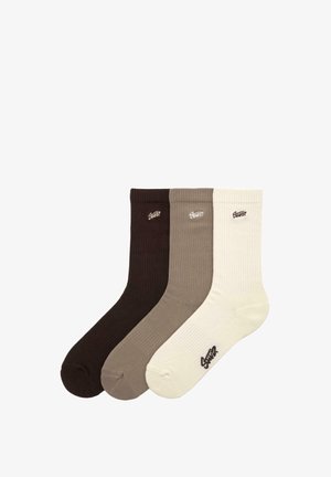 Set tří párů žebrovaných ponožek v tmavě hnědé, světle hnědé a krémové barvě. Každá ponožka má na lemu logo.