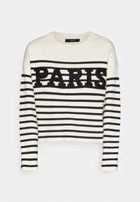 Pull rayé blanc et noir avec le mot « PARIS » affiché en lettres noires texturées de manière proéminente sur la poitrine. Encolure ronde, manches longues.