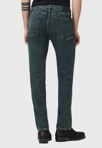 Tmavě zelené džíny z denimu, s rovnými nohavicemi, dvěma zadními kapsami a černou koženou etiketou na pase.