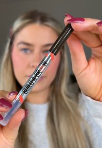 Crayon à sourcils noir avec un design argenté et rouge, arborant le texte "BUILD-A-BROW". Le pinceau est visible à l'extrémité inférieure.