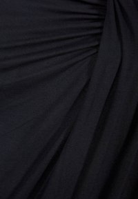 Tessuto nero con una texture plissè. Il materiale è morbido e leggero, con una finitura liscia e un leggero lucido.
