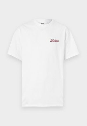 Balta kokvilnas īsroku t-krekls. Uz kreisā krūtīm ir sarkans tekstam līdzīgs logo "Dickies", apaļa kakla izgriezums un standarta piegriezums.