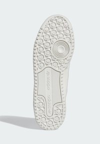 Sola de sapato branca da Adidas com padrões de pisada circulares e retangulares, apresentando o logótipo da Adidas e zonas de aderência texturizadas.