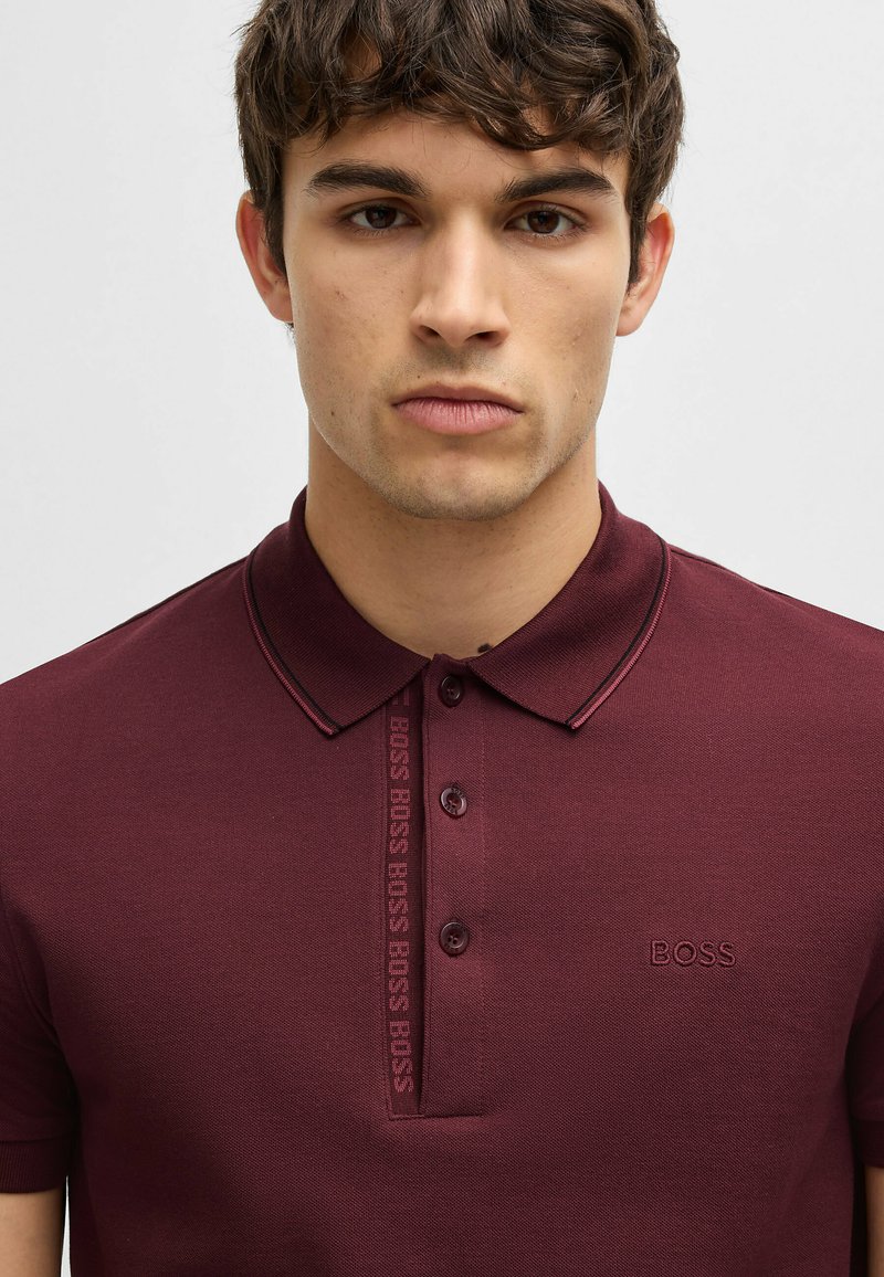 Bordeaux polo shirt van een textuurstof, met een drieknopenboord en subtiele logo-details aan de voorkant en op de borst.