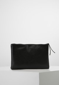 Bolso de mano de cuero negro con textura suave, forma rectangular y cierre de cremallera; presenta una fina pestaña de cuero para tirar.