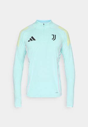 Lichtblauw sportief shirt met lange mouwen en een halve ritssluiting bij de hals, zwarte logo's en gele accenten op de schouders, met roze biezen aan de zijkanten.