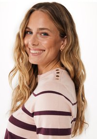 Stribet sweater i lys pink med mørk maroon vandrette striber. Har rund halsudskæring og dekorative guldknapper på skulderen.