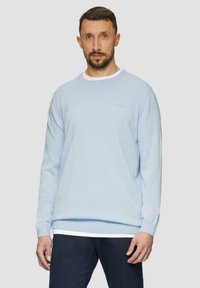 Helles blauer Rundhalspulli aus weichem Material. Verfügt über lange Ärmel und einen Lagenlook mit einem weißen Saum, der am unteren Rand sichtbar ist.