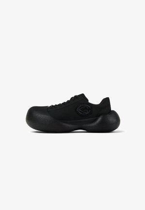 Black sneaker with thick, oversized rounded sole and fabric upper featuring a circular stitched logo on the side.