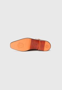 Lædersål med en glat, orange-brun overflade, med subtile mønstre og et præget logo nær hælen.