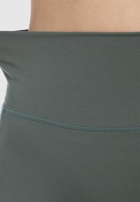 Grijze sportlegging met een brede, gevouwen tailleband. Gemaakt van gladde, rekbare stof, met een naadloos ontwerp en subtiele textuur.