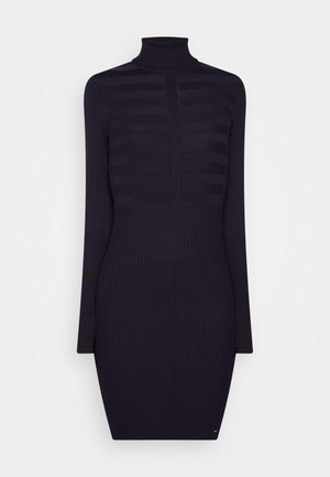 Robe en maille côtelée noire à manches longues et col roulé montant, présentant de subtils motifs de rayures horizontales sur le haut du corps.